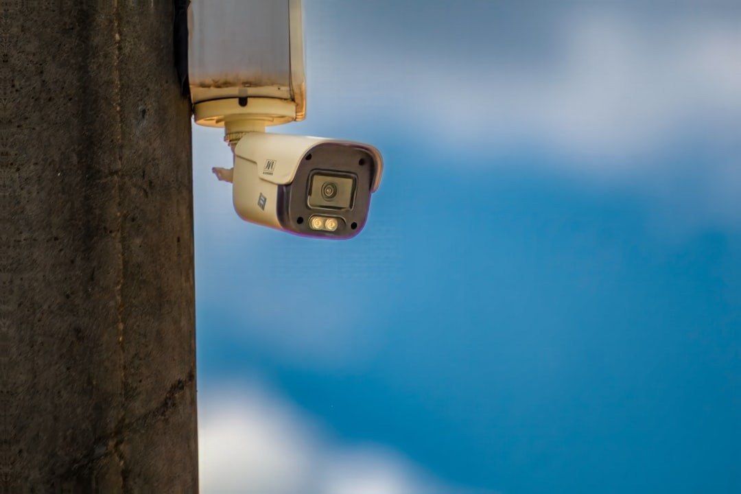 Security camera mounted on a concrete pole under a sky.